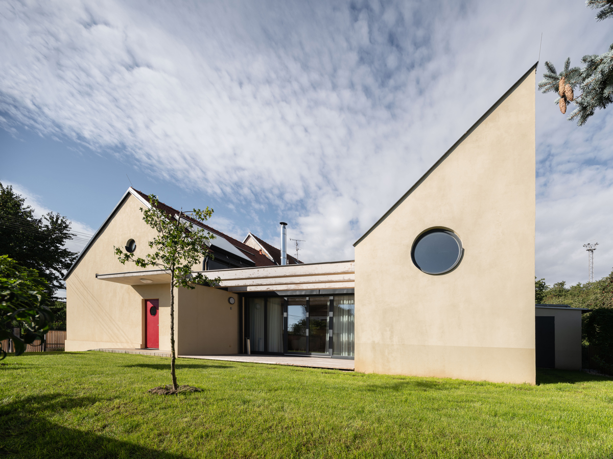 Pohled na zadní část rodinného domu v Křenovicích se zelenou střechou a prosklenou fasádou směrem do zahrady.