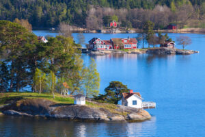 Pohled na typické červené domky na břehu jezera obklopené lesem ve Švédsku.