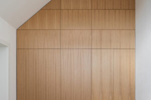 Vestavěné úložné skříně na míru v ložnici rekonstruovaného domu v Křenovicích, s dýhovaným obkladem až ke stropu.