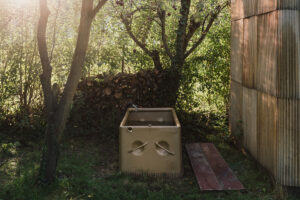 Zahradní ochlazovací vana u sauny z recyklovaných europalet a dřevěných pražců, obklopená zelení.