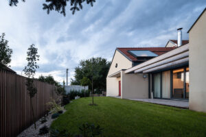 Udržovaná zahrada s mladými stromy a trávníkem u moderní přístavby domu v Křenovicích.