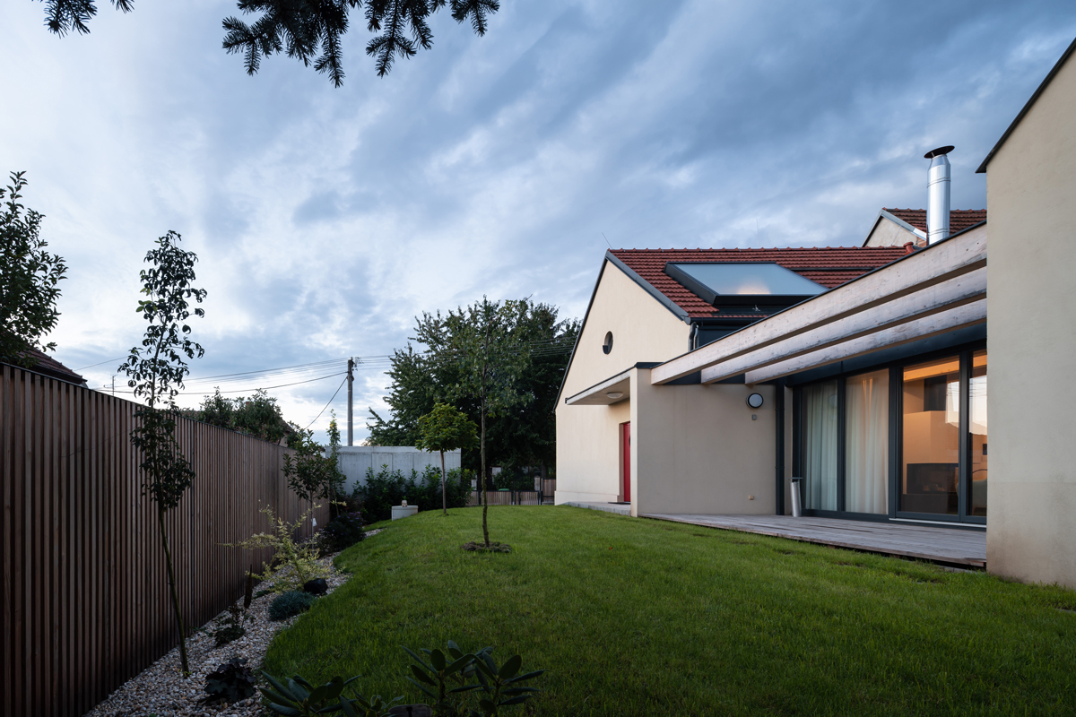 Udržovaná zahrada s mladými stromy a trávníkem u moderní přístavby domu v Křenovicích.