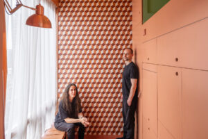 Dvojice architektů stojících v minimalistickém bytě s geometrickou dlažbou.