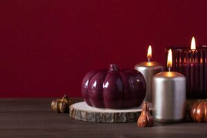 Svíčky a dekorace v odstínu burgundy na dřevěné desce, které navozují elegantní a útulné prostředí.