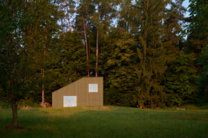 Zelená fasáda splývá s okolním lesem a činí z chaty přirozenou součást valašské krajiny. Jednoduchý tvar stavby podtrhuje její pokoru vůči místu.