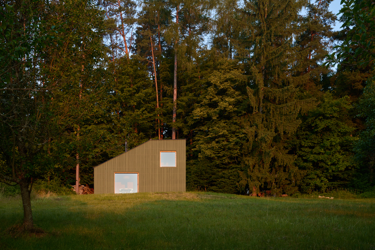 Zelená fasáda splývá s okolním lesem a činí z chaty přirozenou součást valašské krajiny. Jednoduchý tvar stavby podtrhuje její pokoru vůči místu.