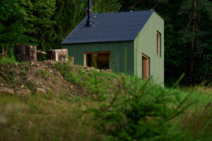 V ranním světle působí stavba téměř jako součást lesa. Architektura zde nesoutěží s přírodou, ale tichým způsobem ji doplňuje.
