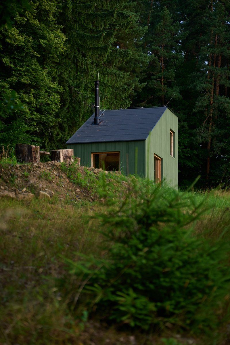 V ranním světle působí stavba téměř jako součást lesa. Architektura zde nesoutěží s přírodou, ale tichým způsobem ji doplňuje.