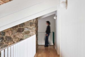 Moderní lávka nad obytným prostorem nechává vyniknout původnímu kamennému zdivu, které se stalo jedním z nejcennějších prvků rekonstrukce.