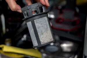 Ruka drží vyjmutý filtr z myčky určený k pravidelnému čištění.