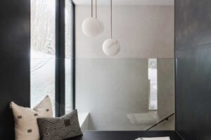 Pohodlný čtecí koutek s polštáři a dekou u okna.