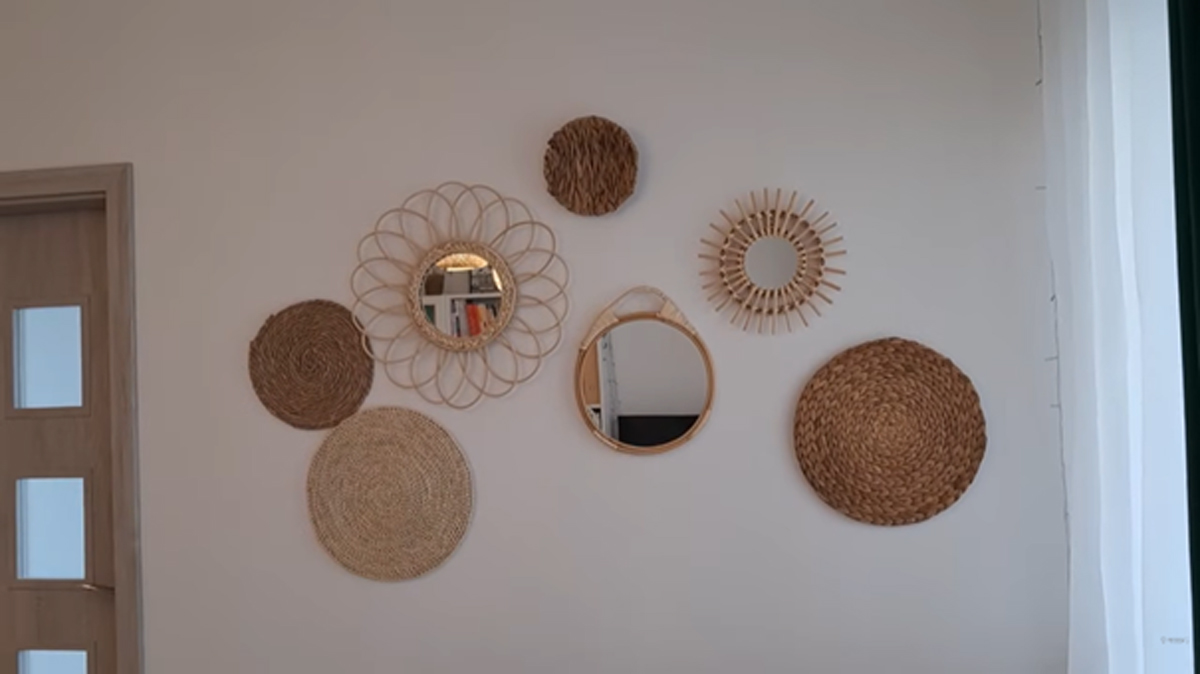 Stěna v obývacím pokoji s dekoracemi a zrcadly z proutí a ratanu.
