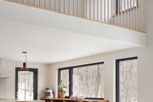 Otevřený obytný prostor propojený s horní lávkou ukazuje, jak rekonstrukce vytvořila světlý, plynoucí interiér orientovaný směrem k přírodě.