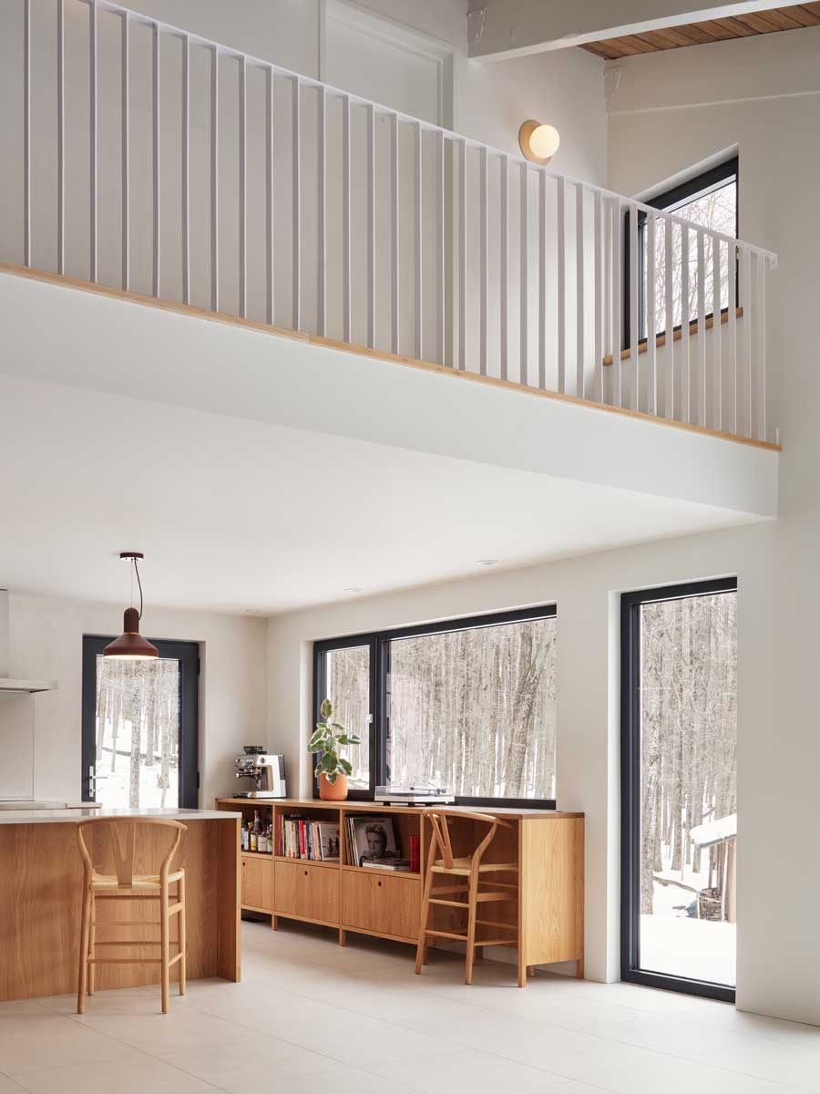Otevřený obytný prostor propojený s horní lávkou ukazuje, jak rekonstrukce vytvořila světlý, plynoucí interiér orientovaný směrem k přírodě.