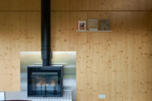 Černý krb s kovovým obkladem je výrazným kontrastem k teplému tónu dřeva. Minimalistická forma a čisté linie dávají prostoru moderní, avšak útulný charakter.