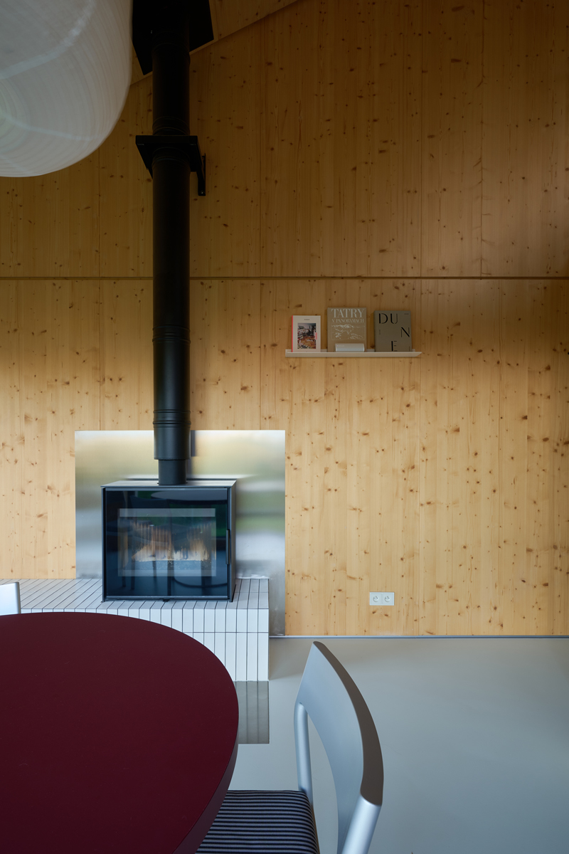 Černý krb s kovovým obkladem je výrazným kontrastem k teplému tónu dřeva. Minimalistická forma a čisté linie dávají prostoru moderní, avšak útulný charakter.