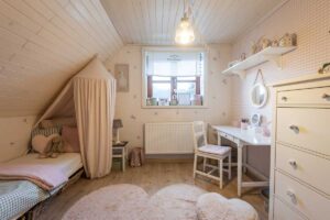 Dívčí pokoj v jemných pastelových tónech s baldachýnem, měkkým kobercem a bílým psacím stolem.