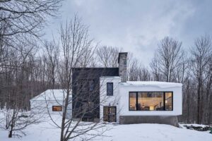 Nová fasáda kombinuje čisté bílé linie s tmavým objemem, čímž zdůrazňuje členitost původní chaty a její propojení s krajinou.