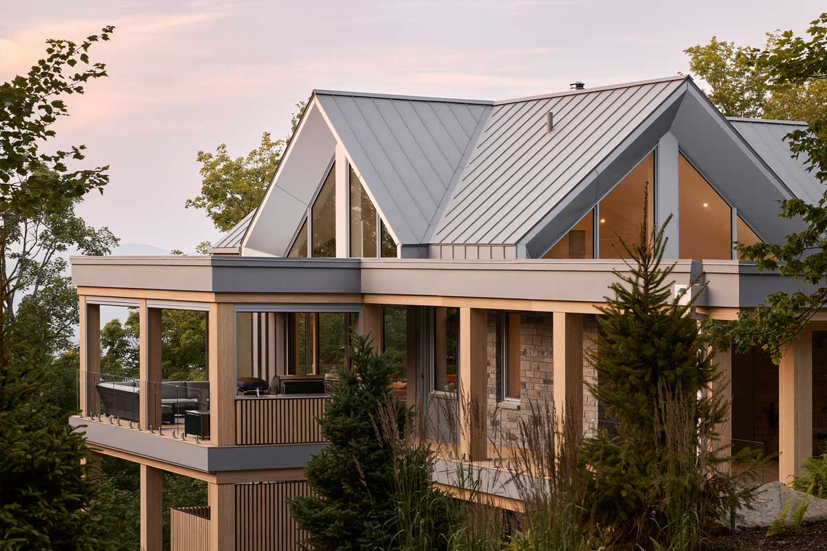 Pohled na horní podlaží domu ukazuje, jak se geometrie trojúhelníků a písmena A opakuje na fasádě a zachytává světlo