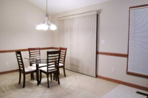 Jednoduchá jídelna s prázdnou stěnou a základním nábytkem.