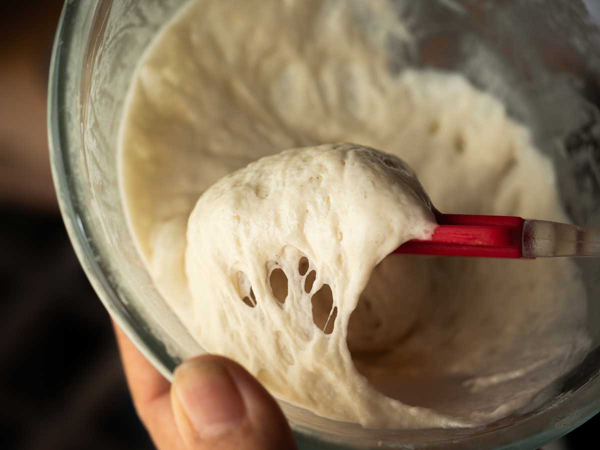 Detail na pružné kynuté těsto nabrané silikonovou stěrkou z mísy.