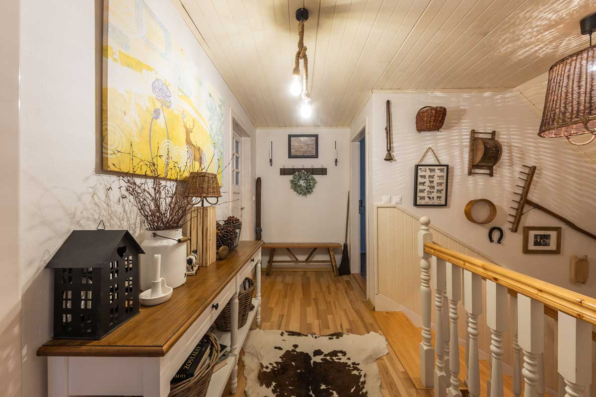 Chodba v horním patře roubenky s dekoracemi z přírodních materiálů a tradičními venkovskými prvky.