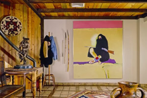 Interiér s dřevěným obložením, obrazem, sochou a dekoracemi inspirovanými původními kulturami.