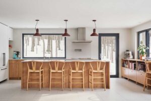 Nové uspořádání kuchyně využívá široká okna směrem do lesa, aby interiér působil světle, přirozeně a organicky navázaný na okolní přírodu.