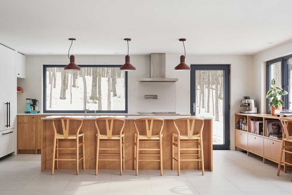 Nové uspořádání kuchyně využívá široká okna směrem do lesa, aby interiér působil světle, přirozeně a organicky navázaný na okolní přírodu.