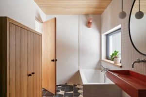 Zrekonstruovaná koupelna spojuje přírodní materiály s hravou geometrií dlažby, která přináší do tradiční horské chaty moderní charakter.