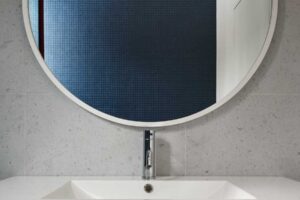 Minimalistický detail koupelnového zrcadla odhaluje střídmou kombinaci dřeva a dlaždic, navazující na celkový přírodní tón interiéru.