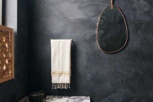 Stylová koupelna s tmavými stěrkami a mramorovým umyvadlem.