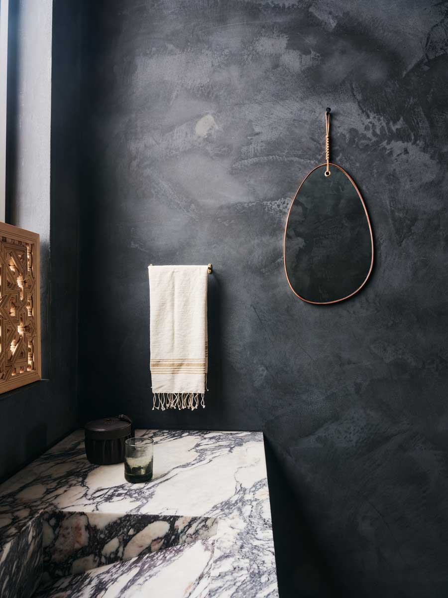 Stylová koupelna s tmavými stěrkami a mramorovým umyvadlem.