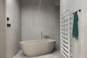 Minimalistická koupelna s volně stojící vanou v béžovo-šedých tónech působí klidně a harmonicky.