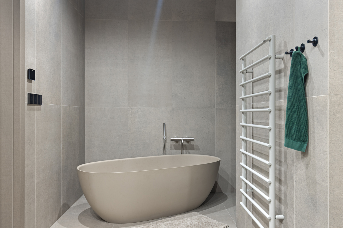 Minimalistická koupelna s volně stojící vanou v béžovo-šedých tónech působí klidně a harmonicky.