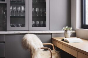 Domácí pracovní kout s dřevěným stolem a židlí potaženou kožešinou.