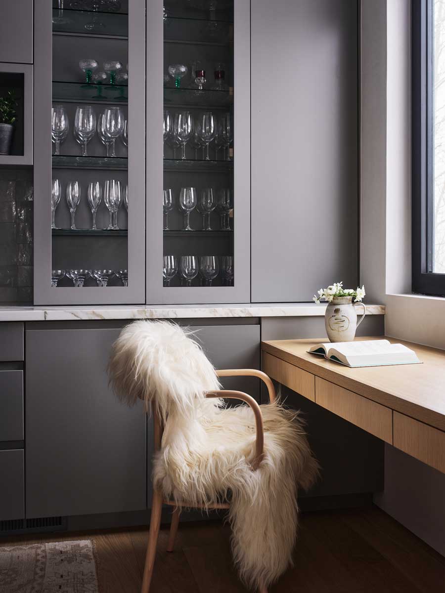 Domácí pracovní kout s dřevěným stolem a židlí potaženou kožešinou.