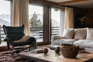 Relaxační kout s vintage křeslem a recyklovanými prvky, které doplňují výhled na švýcarské Alpy.