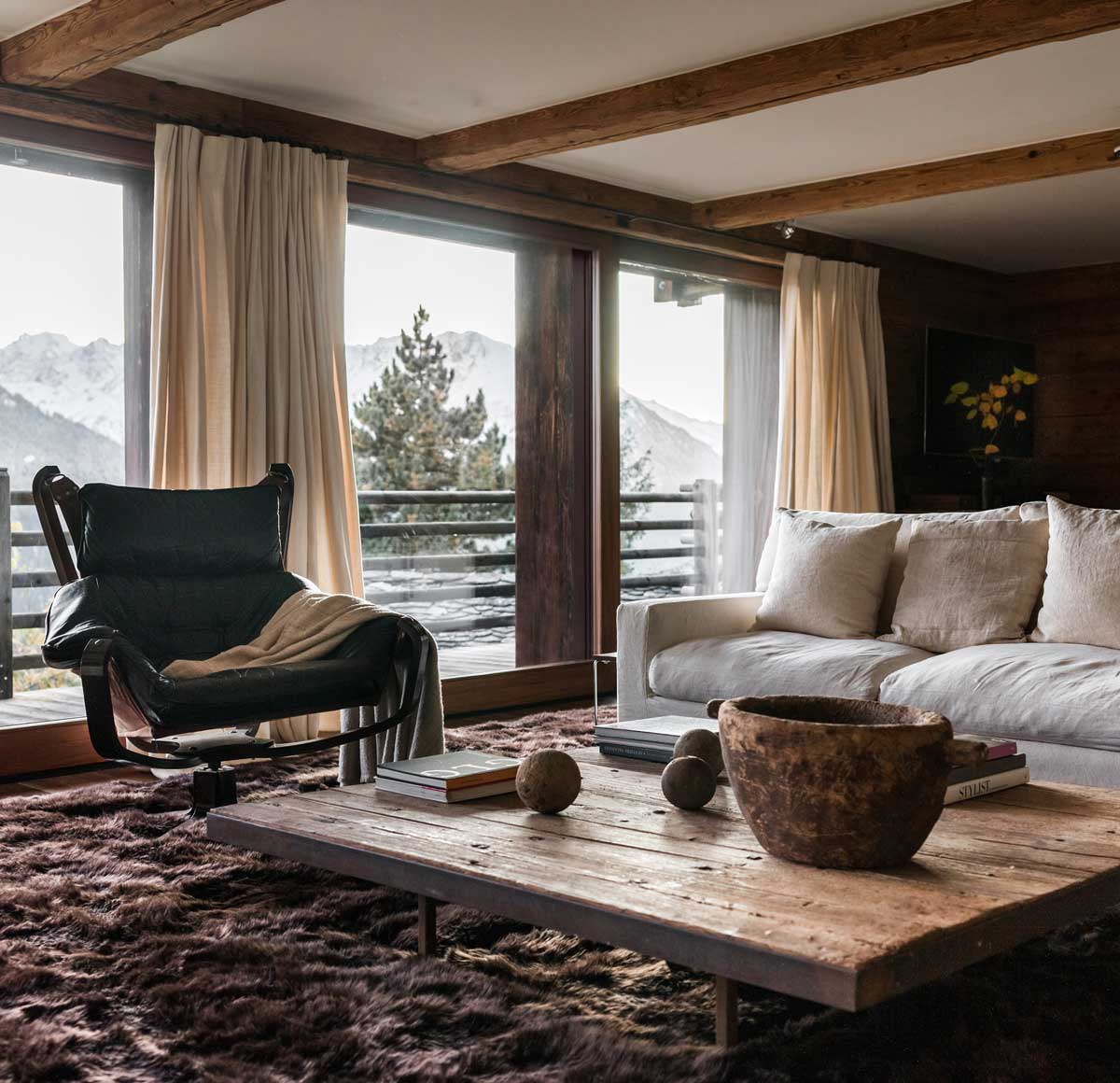 Relaxační kout s vintage křeslem a recyklovanými prvky, které doplňují výhled na švýcarské Alpy.