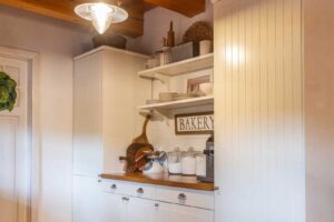 Venkovská kuchyně s bílou linkou a dřevěnými prvky.