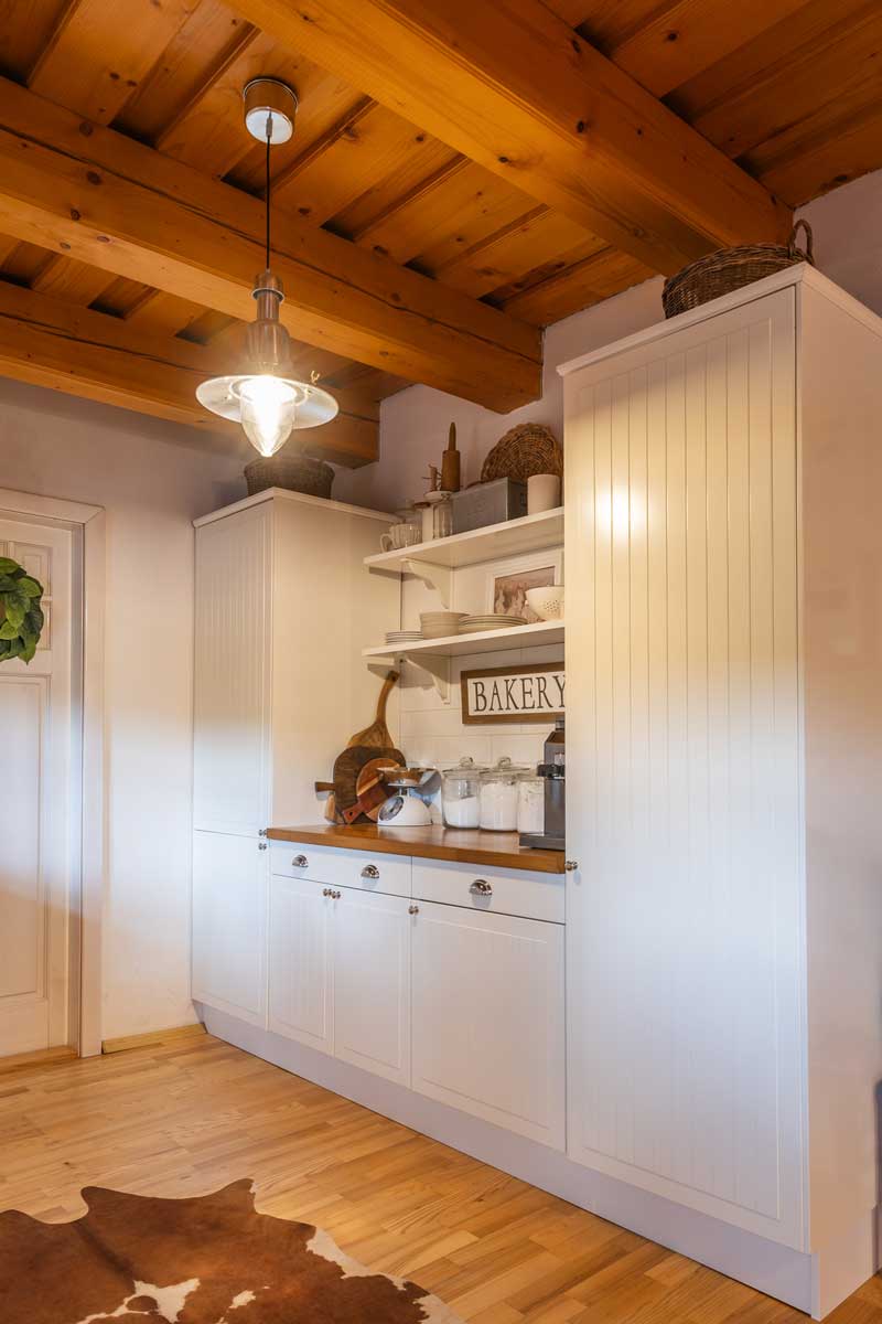 Venkovská kuchyně s bílou linkou a dřevěnými prvky.