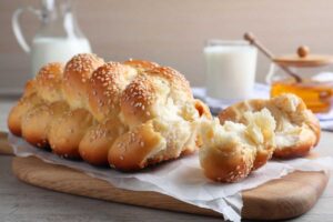 Domácí pletená vánočka se sezamem připravená z kynutého těsta a servírovaná s mlékem a medem.