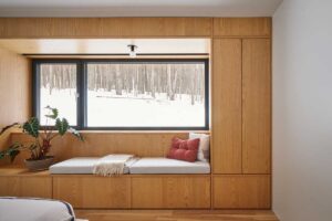 Vestavěná lavice pod širokým oknem nabízí klidné místo k odpočinku, odkud lze pozorovat proměny horské krajiny během celého roku.