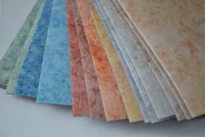 Vzorník linolea v různých barvách od modré po oranžovou s jemnou strukturou povrchu.