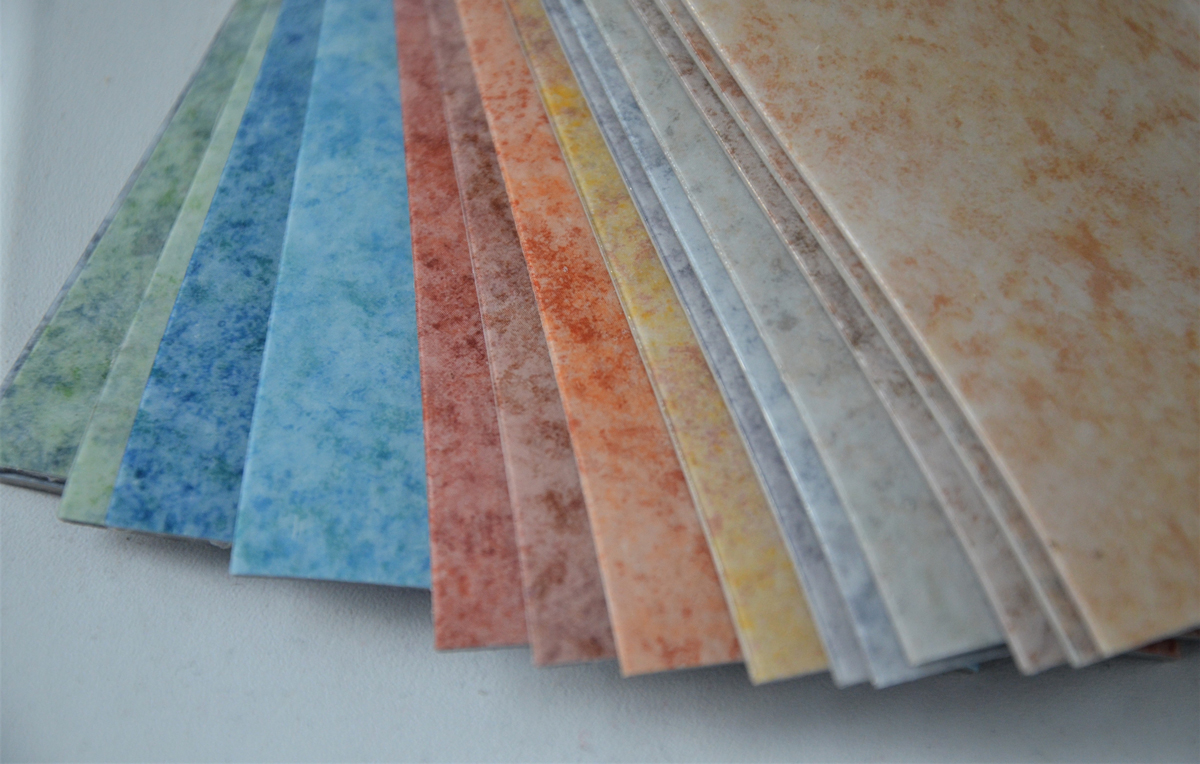 Vzorník linolea v různých barvách od modré po oranžovou s jemnou strukturou povrchu.