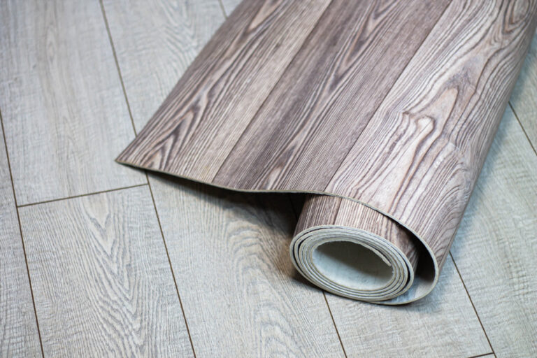 Rolované linoleum s dekorem světlého dřeva položené na podobně zbarvené podlaze.