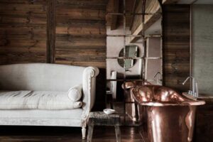 Recyklovaná měděná vana doplněná vintage zrcadly a přírodními povrchy, odkazující na filozofii cirkulárního designu.