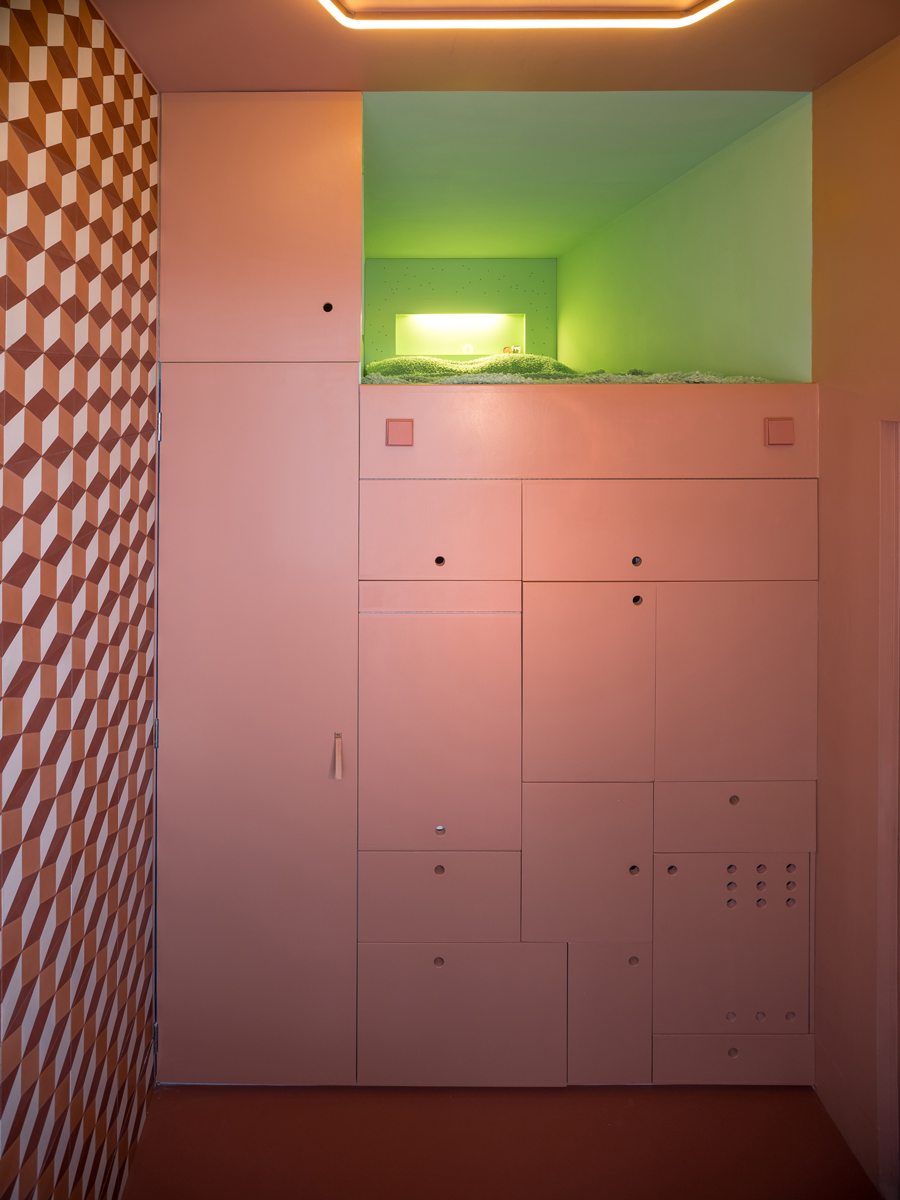 Interiér mikrobytu s vestavěným úložným prostorem a zelenou ložnicovou nikou.