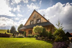 Roubenka v odpoledním slunci s pečlivě upravenou zahradou a bujnou zelení v popředí.