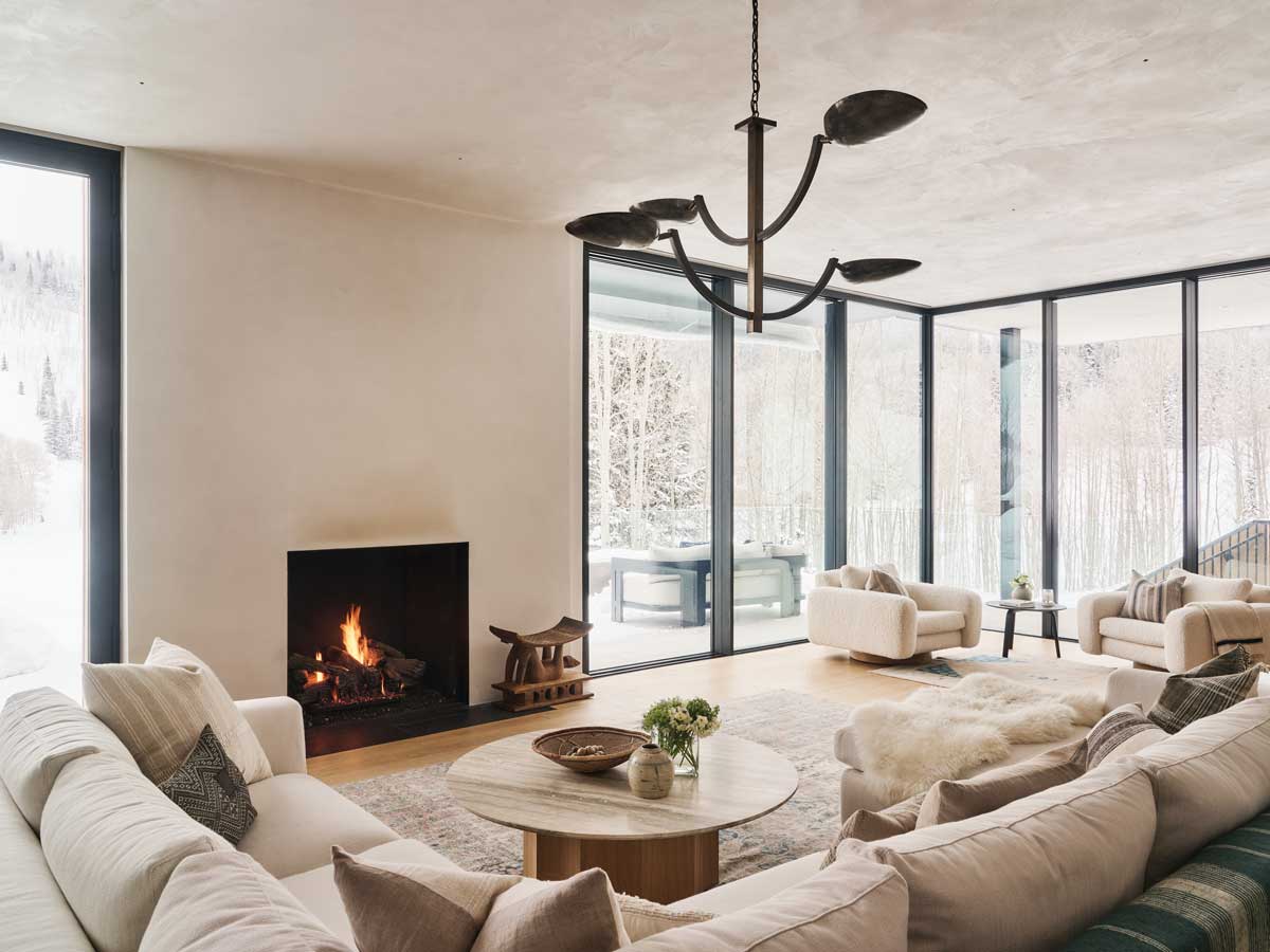 Obývací pokoj s krbem, pohodlnými sedačkami a panoramatickými okny.